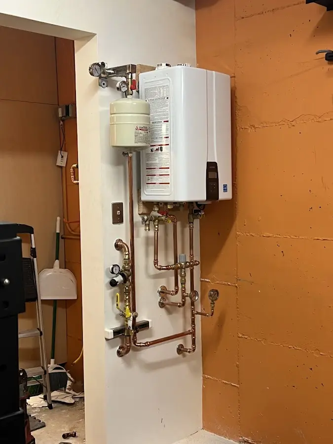 Plumbing technician inspecting water heater connections in Adams